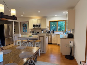 A modern kitchen with a central island, stainless steel appliances, and a view of the outdoors. - Luxury Chalet on 1.5 Acres: Mountain Views, Hot Tub, Gym, fire pit & Ping-Pong (Windham)