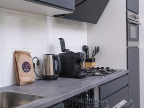 Una cocina moderna con estufa a gas, cafetera, hervidor y una bolsa de café.