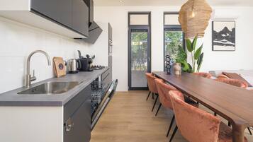 Eine moderne Küche mit integriertem Geschirrspüler, Spüle und Herd. Es gibt einen Essbereich mit einem Holztisch und Stühlen.