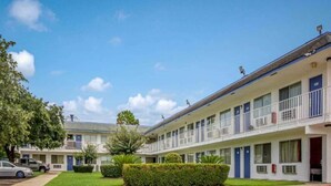 Een motel met meerlaagsgebouwen, elk met een balkon en een deur met een nummer.