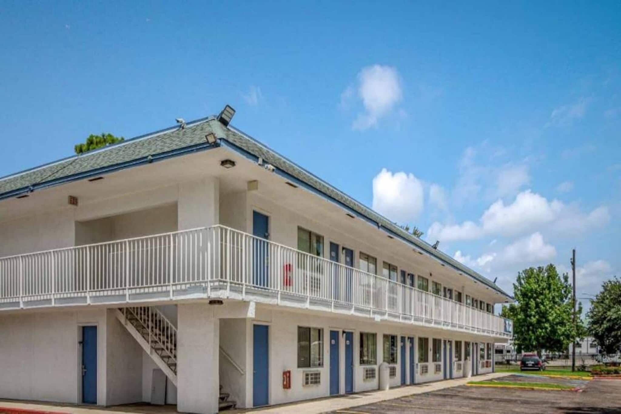 A motel with a covered front porch and a staircase leading to the entrance.