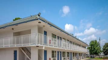 A motel with a covered front porch and a staircase leading to the entrance.