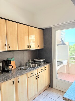 A modern kitchen with wooden cabinets, a granite countertop, and a built-in sink. - Superb apartment on the port of St Cyprien (Saint-Cyprien)