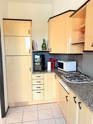 Une cuisine compacte avec des meubles en bois, une cuisinière à gaz, un four à micro-ondes et un grille-pain.