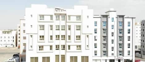 A multi-story hotel with a central entrance and a parking lot in front.