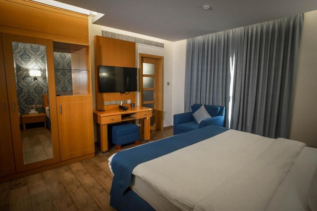 Une chambre d’h ôtel équipée d’un lit, d’un bureau, d’une chaise, d’une télévision et d’une armoire.