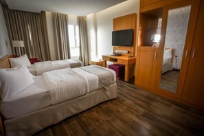 Habitación de hotel con dos camas, un escritorio, televisor y armario.