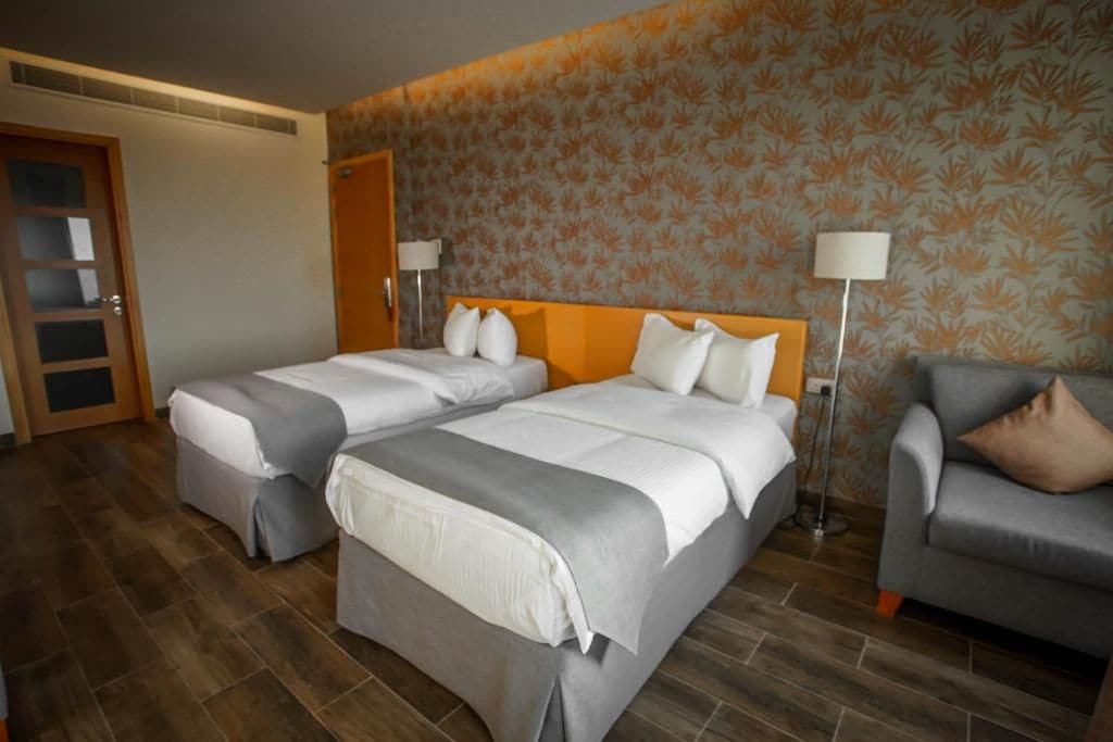 Ein Hotelzimmer mit zwei Betten, einer Couch und einem Wandpapier mit Muster.