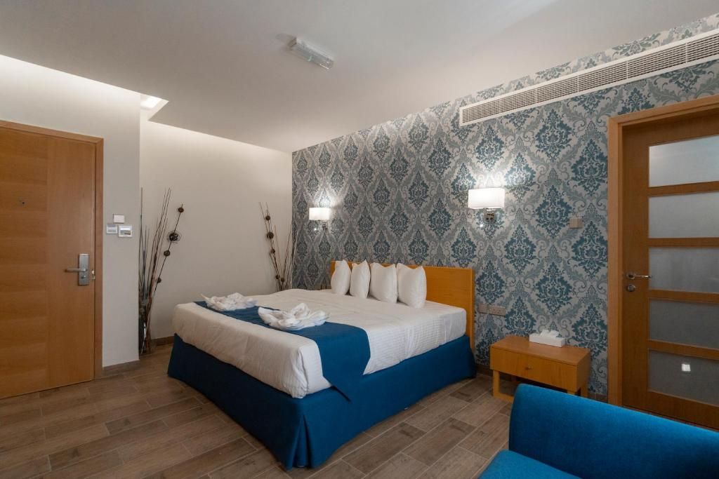 A hotel room with a bed, bedside table, and a blue sofa.