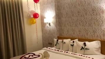 Ein Hotelzimmer mit einem Bett, Kissen, einer Wandleuchte und Luftballons.