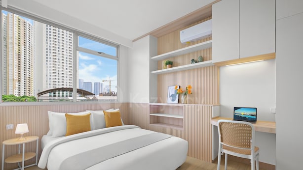 Quarto moderno com uma cama grande, uma escrivaninha e vista para edifícios altos.