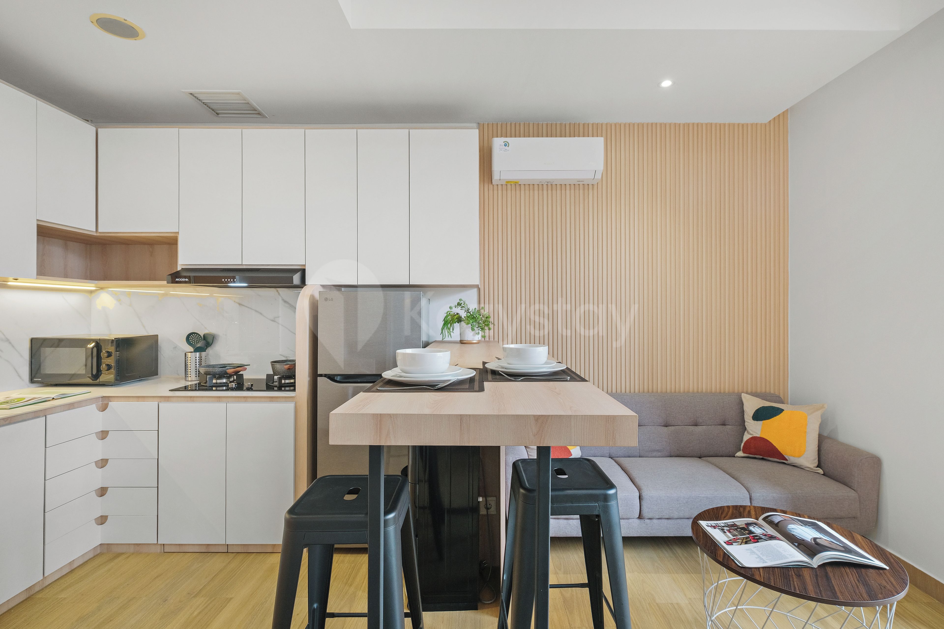 Una cocina compacta con electrodomésticos modernos, un comedor con taburetes y una sala de estar con sofá.