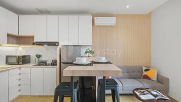 Una cocina compacta con electrodomésticos modernos, un comedor con taburetes y una sala de estar con sofá.