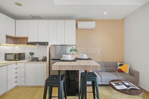 Una cocina compacta con electrodomésticos modernos, un comedor con taburetes y una sala de estar con sofá.