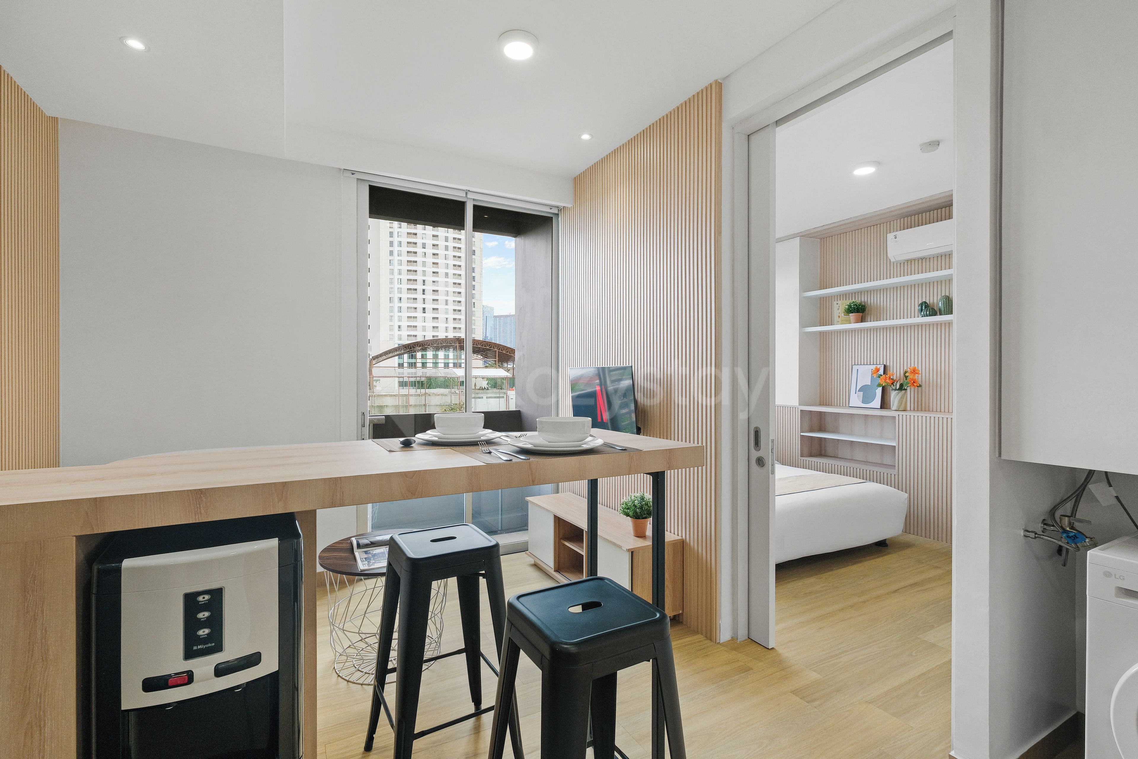 Una cocina moderna con refrigerador incorporado, un comedor con mesa de madera y vista a la ciudad a través del ventanal.