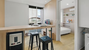 Cozinha moderna com geladeira embutida, área de refeições com mesa de madeira e vista para a cidade através da janela.