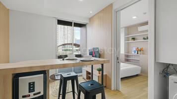 Una cocina moderna con refrigerador incorporado, un comedor con mesa de madera y vista a la ciudad a través del ventanal.