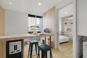 Una cocina moderna con refrigerador incorporado, un comedor con mesa de madera y vista a la ciudad a través del ventanal.