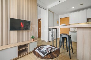 Una cocina moderna con lavadora integrada, un banco de madera y una mesa redonda con una revista.