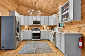 A modern kitchen with stainless steel appliances, grey cabinets, and a wooden ceiling. - Hothouse Creek Retreat - Fishing Access, Firepit & Large Outdoor Space (Mineral Bluff)