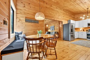 A wooden interior with a dining area, kitchen, and seating. - Hothouse Creek Retreat - Fishing Access, Firepit & Large Outdoor Space (Mineral Bluff)