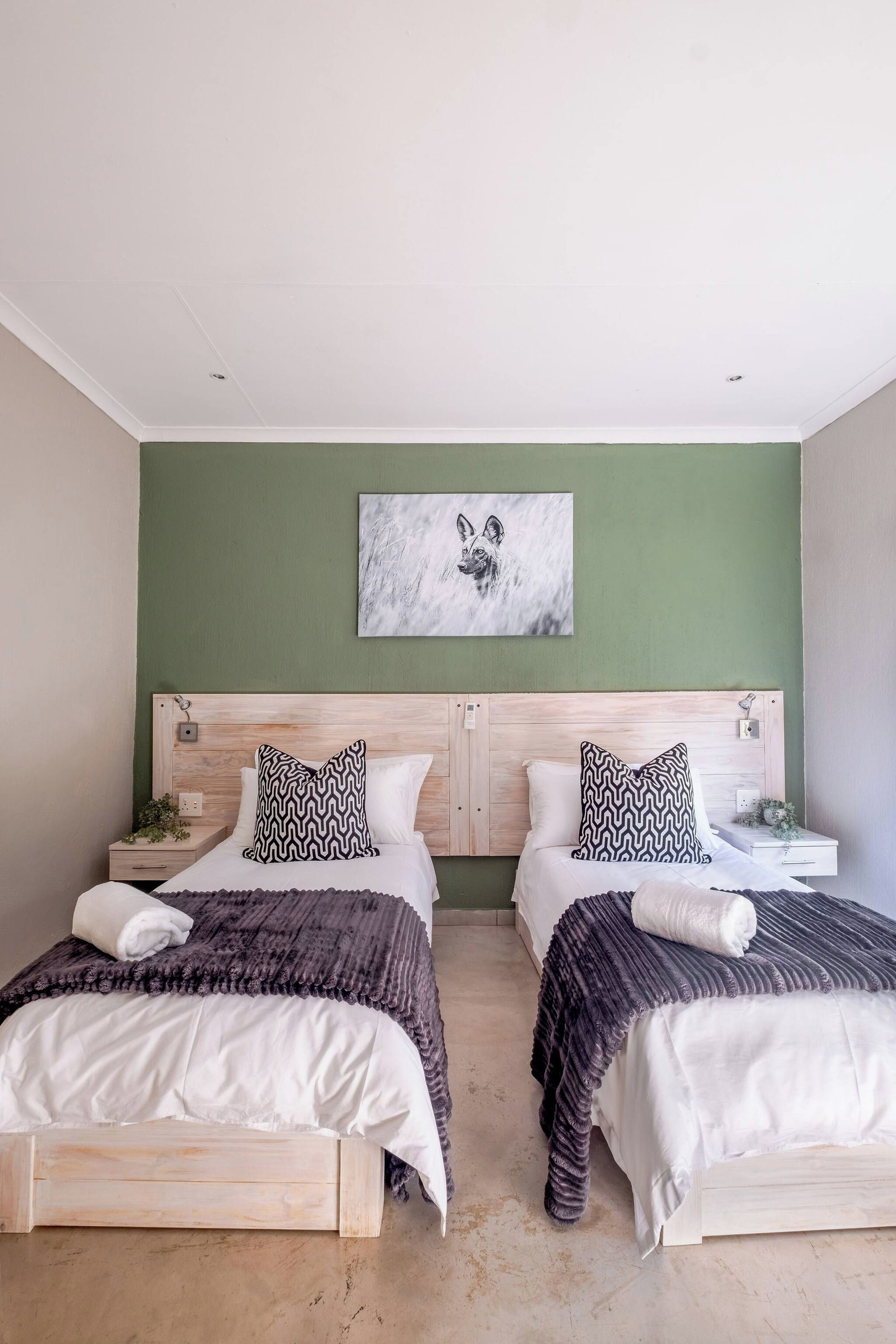 A hotel room with two beds, a green wall, and a ceiling light.