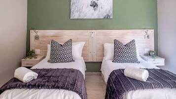 A hotel room with two beds, a green wall, and a ceiling light.