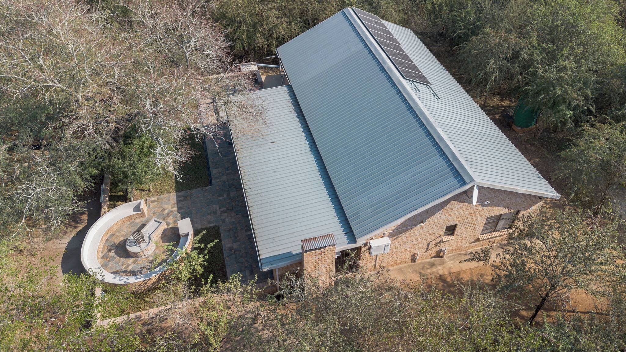 A single-story building with a flat roof, surrounded by trees and vegetation.