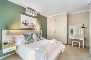 Un dormitorio con cama, escritorio, armario y aire acondicionado instalado en la pared.