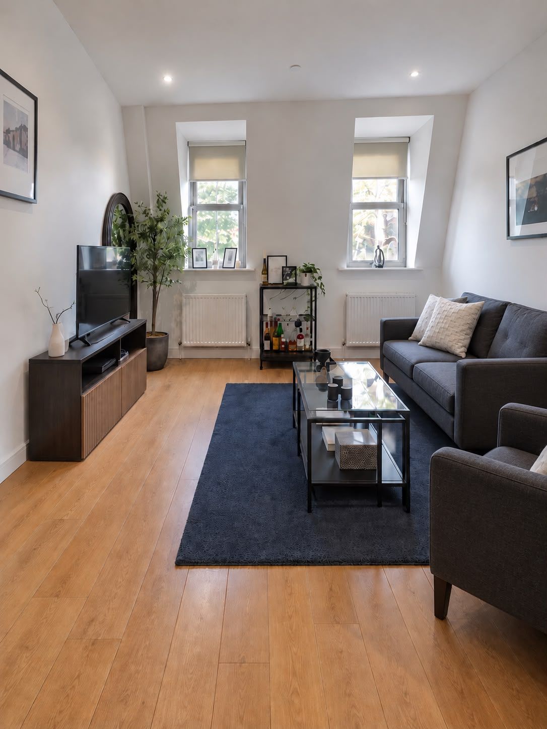 A modern living room with a flat-screen TV, a sofa, a coffee table, and a bookshelf.