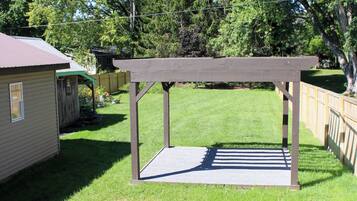A backyard with a wooden pergola, a small shed, and a fenced area.