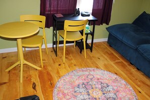 Una habitación con piso de madera redonda, un sofá azul, una mesa amarilla y dos sillas amarillas.