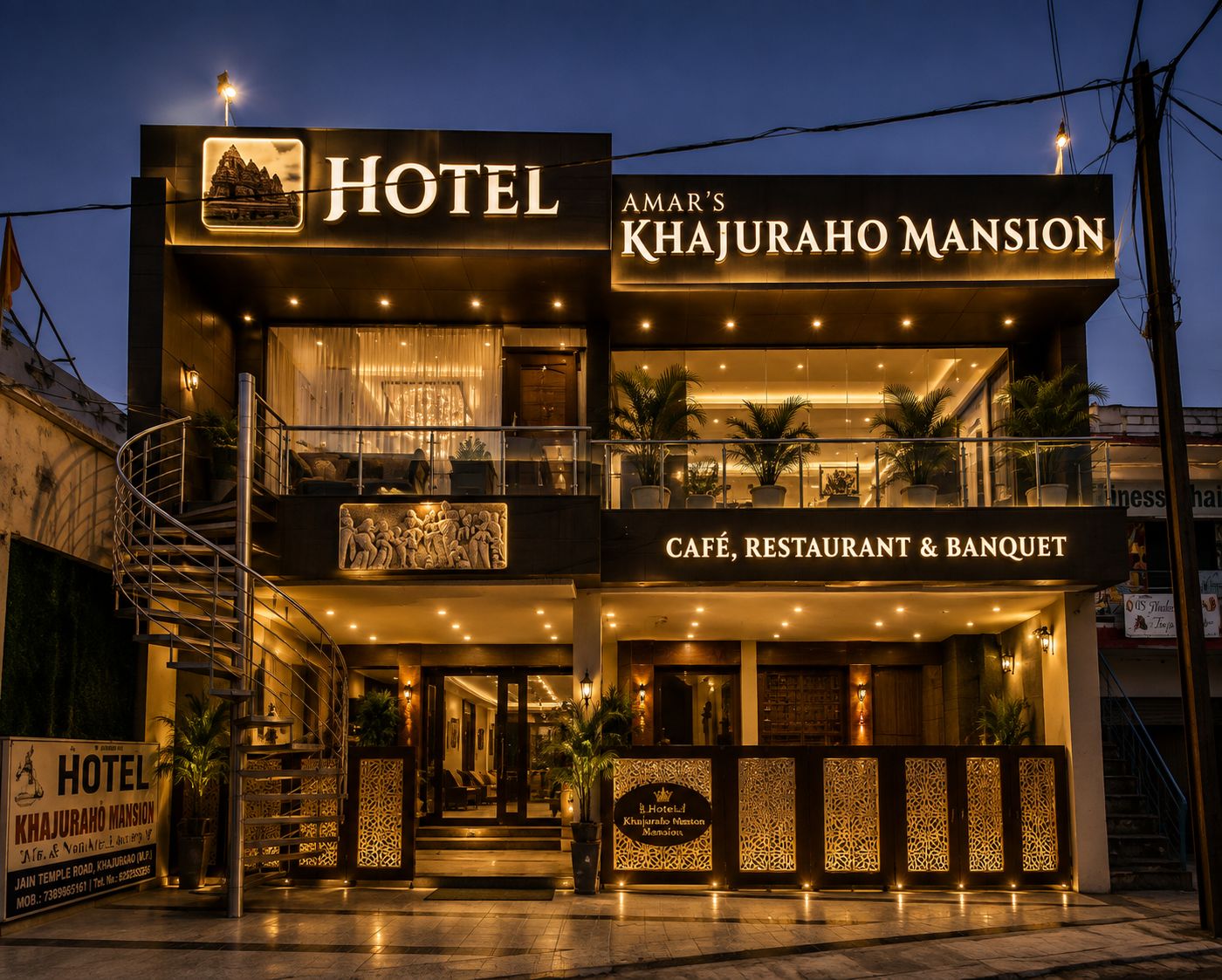 A hotel with a sign indicating it is 'Amar's Khajuraho Mansion' and has a cafe, restaurant, and banquet.
