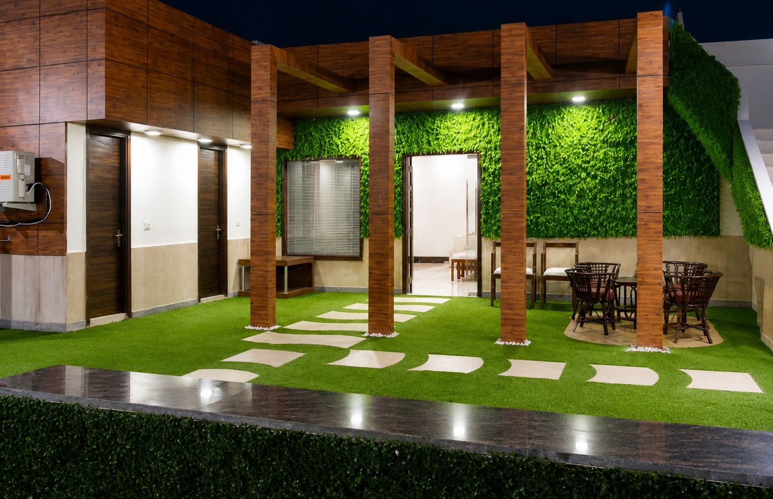 Un espacio exterior moderno con césped artificial, una zona de estar y una pared cubierta de follaje verde.