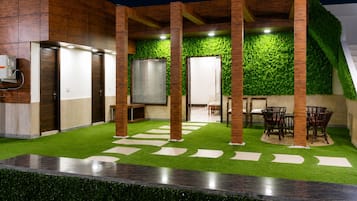 Un espacio exterior moderno con césped artificial, una zona de estar y una pared cubierta de follaje verde.