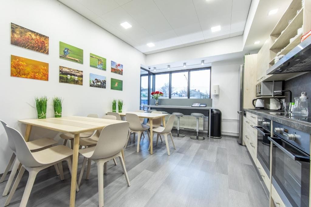 A modern kitchen with a dining area, featuring a large window, a refrigerator, and a sink.
