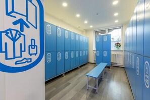 Un vestuario con taquillas azules, un banco y una pared con iconos.