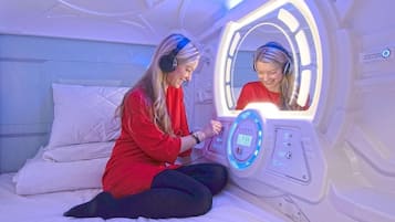 A person sitting on a bed in a room with a massage therapy machine.