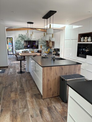 A modern kitchen with a wooden island, white cabinetry, and a built-in oven.