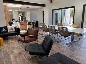 A modern interior with a dining area, seating arrangements, and a kitchen in the background.