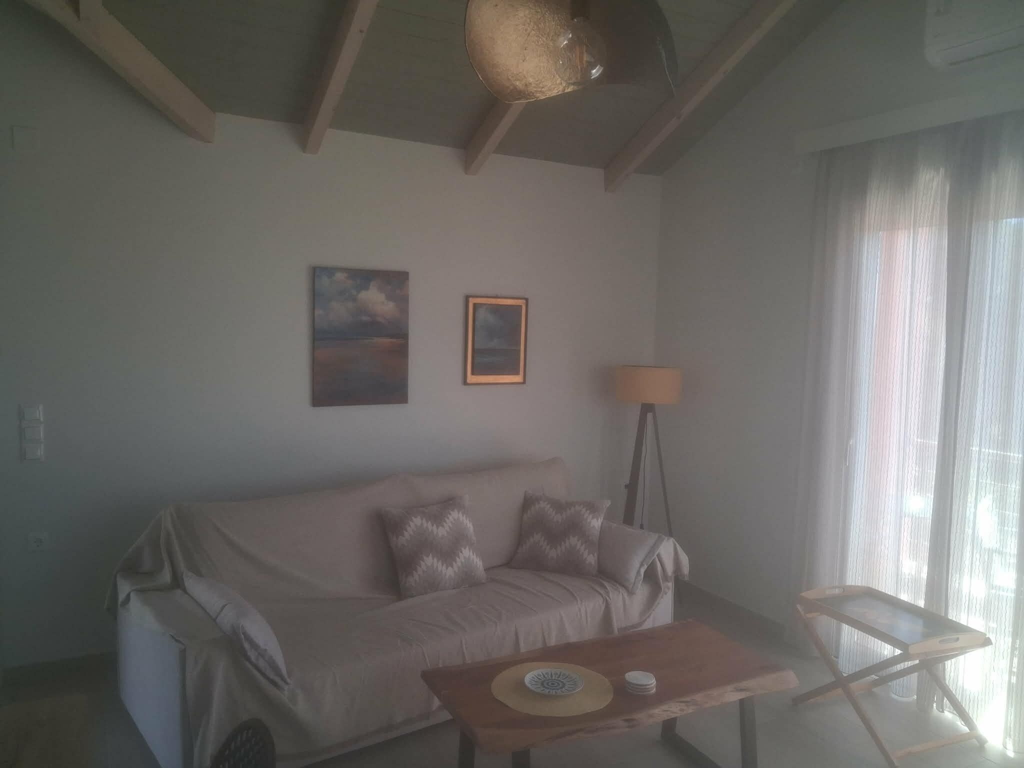 Una sala de estar con un sofá, una mesa con un plato y una taza, una lámpara y dos cuadros en la pared.