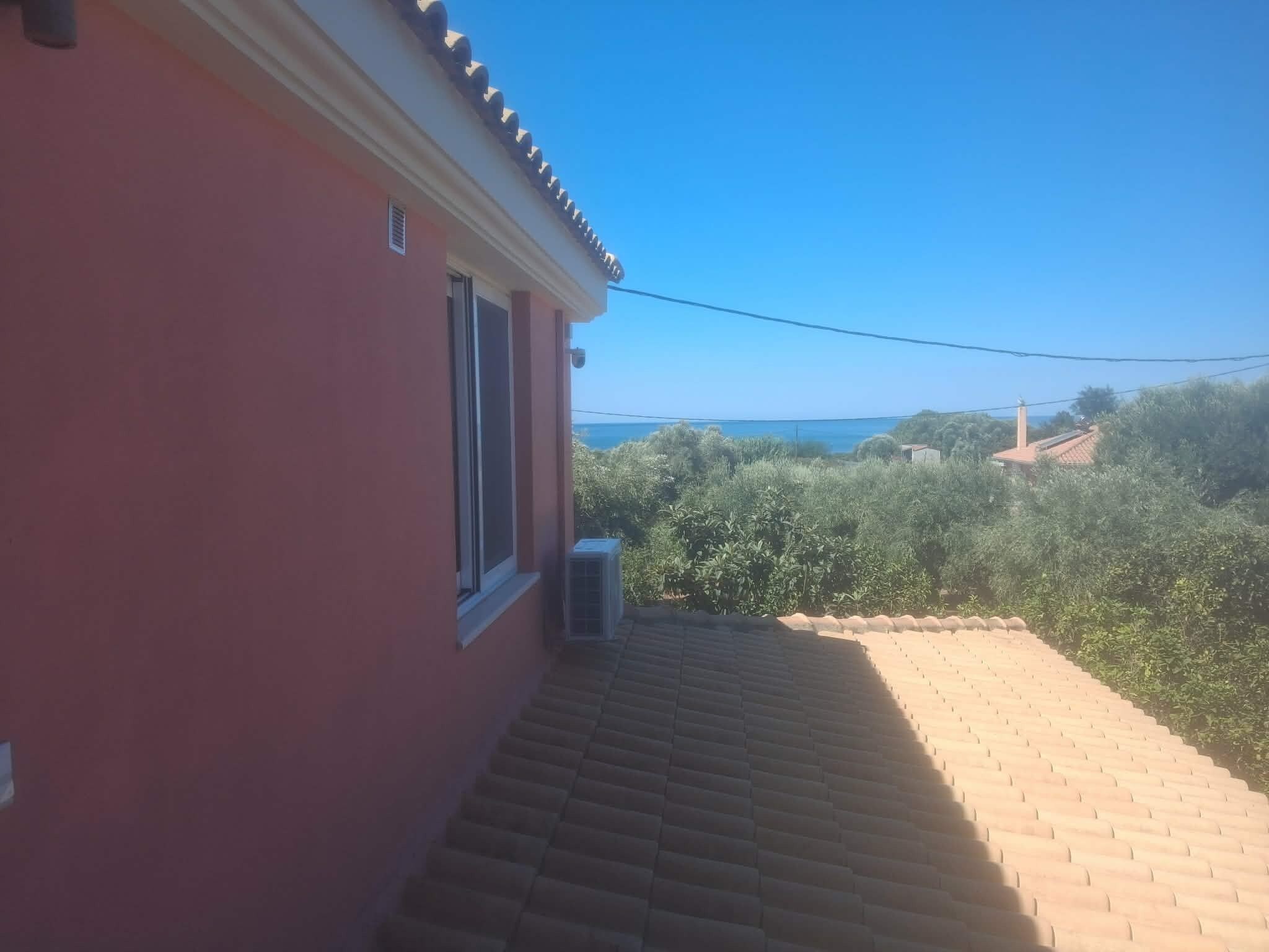 A red building with a tiled roof, a window, and an air conditioning unit.