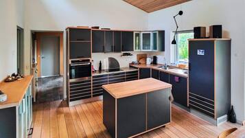 A modern kitchen with wooden flooring, built-in cabinets, and a central island.