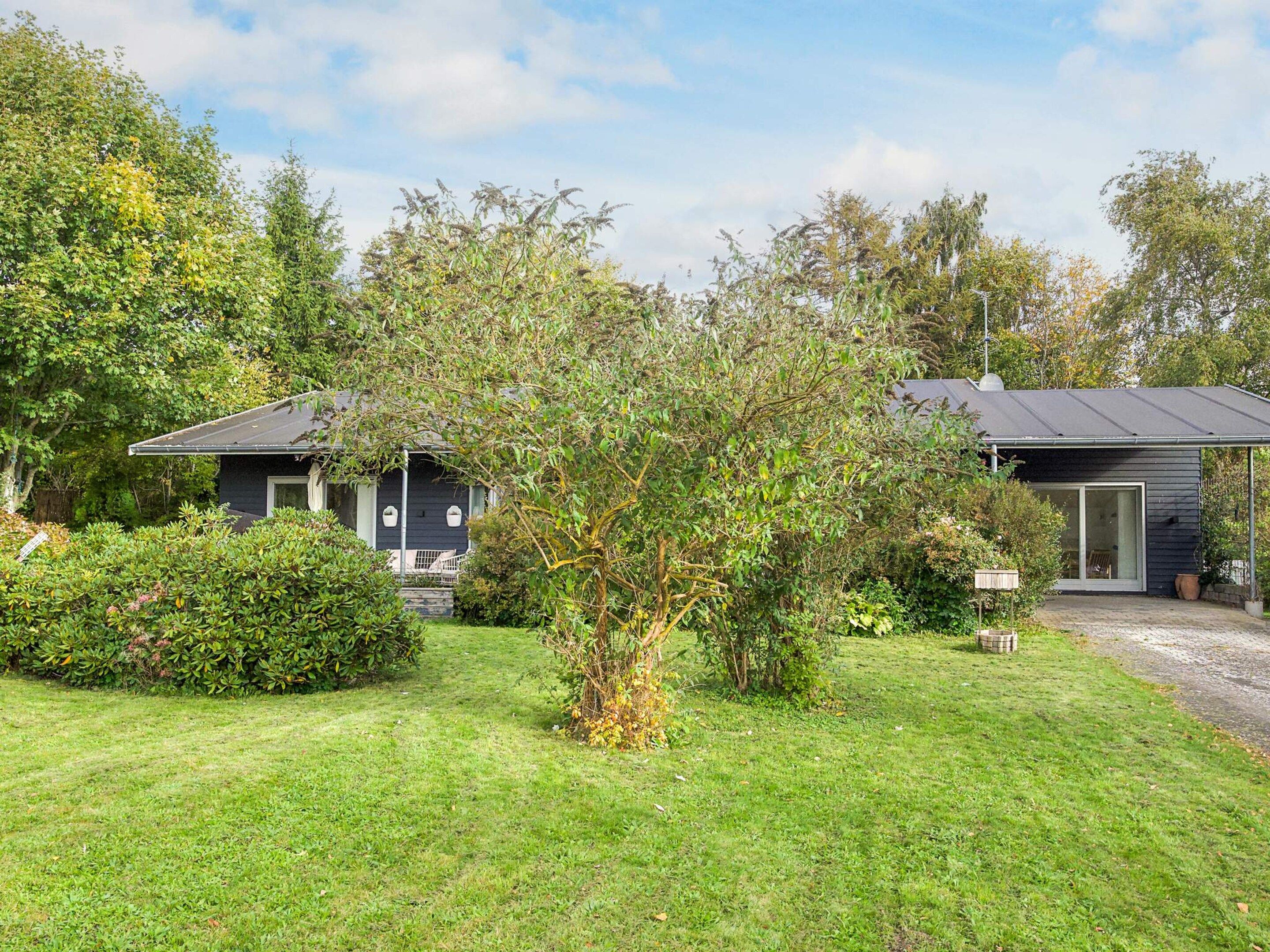A modern house with a well-maintained lawn and a variety of trees and shrubs.
