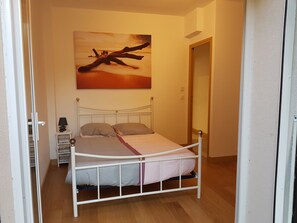 A bedroom with a bed, bedside table, lamp, and a painting on the wall. - Apartment 'Les Orangers' with Private Garden, Wi-Fi and Air Conditioning (Cannes)