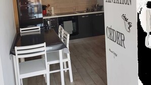 A modern kitchen with black cabinets, a wooden countertop, and a dining area with white chairs. - Apartment 'Les Orangers' with Private Garden, Wi-Fi and Air Conditioning (Cannes)