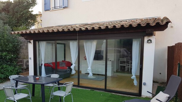 A patio with a table, chairs, and a red sofa. - Apartment 'Les Orangers' with Private Garden, Wi-Fi and Air Conditioning (Cannes)