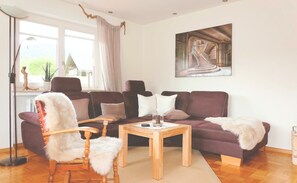 Ein Wohnzimmer mit einer Couch, Sesseln, einem Couchtisch und einem Bild an der Wand.
