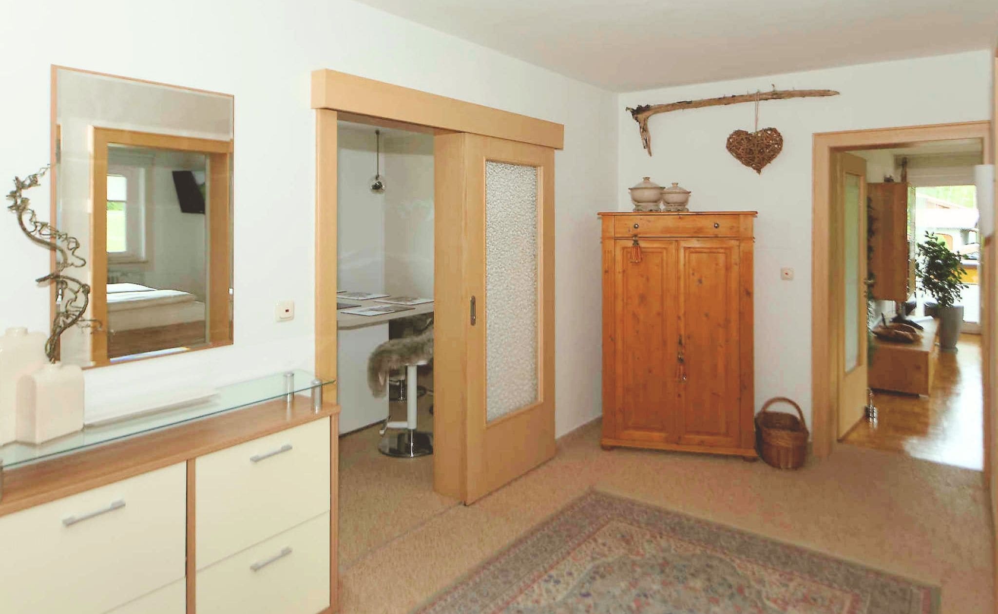 A room with a mirror, a wardrobe, a small cabinet, a rug, and a heart-shaped decoration on the wall.