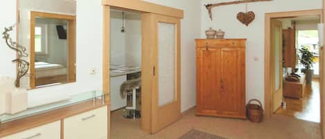 A room with a mirror, a wardrobe, a small cabinet, a rug, and a heart-shaped decoration on the wall.